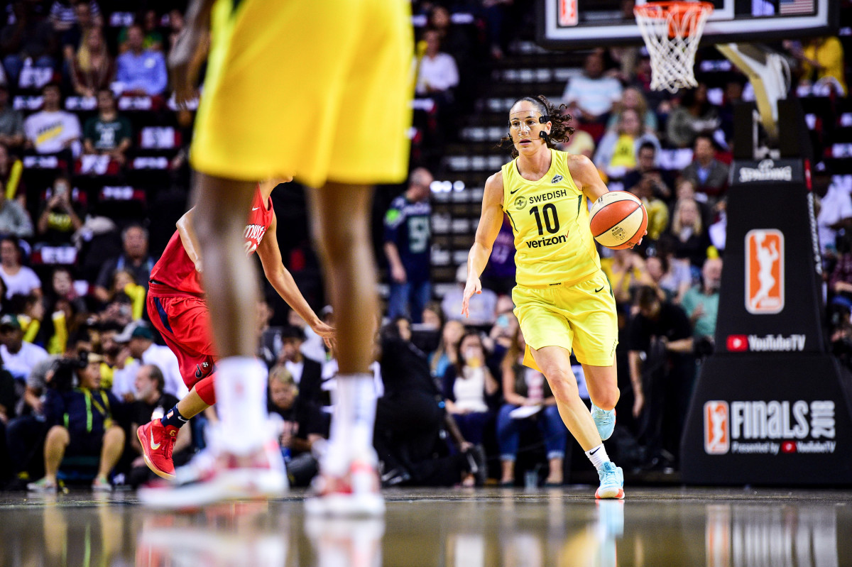 Sue Bird dribbles, wearing a nose mask